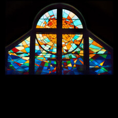 Large, abstract altar window symbolizing the rising sun with multicolored rays. The palette was chosen to represent a multitude of faiths, symbolizing the unity of all people and their welcome to services at Our Lady of Mercy.