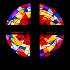 Abstract design of Rose Window over the sanctuary entrance depicts the universal symbol of the setting sun. A variety of glass was utilized including antique and machine glass.
